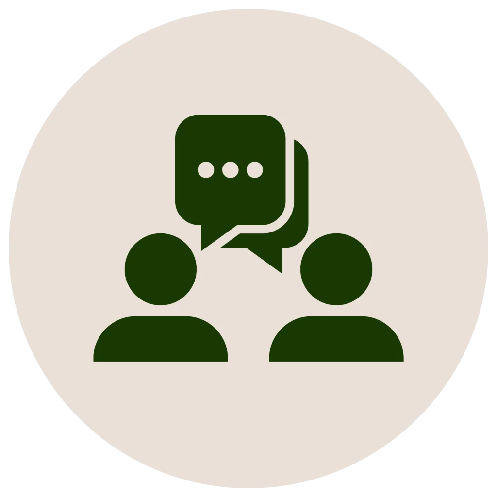 Minimalist flat icon of two people silhouettes with overlapping speech bubbles inside a circle, in a dark green silhouette on an off-white background.