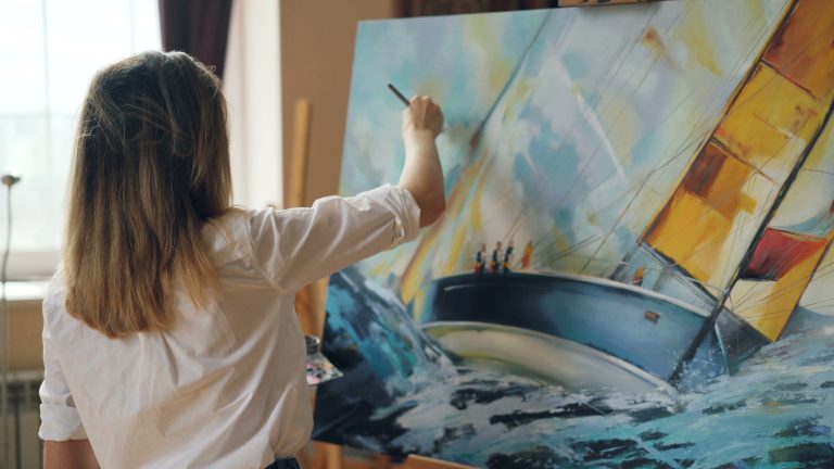 Artist painting a large sailboat canvas showcasing types of art medium.